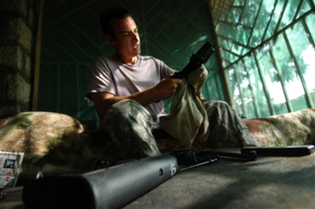 U.S. Army Sgt. Chris Lyke cleans his M-4 rifle in his living space at the Gode Hotel in Gode, Ethiopia, July 22, 2006. 