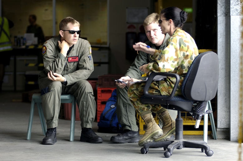 Maj. Landon Henderson (left) and Capt. Todd Strickland talk to Warrant Officer Vivianne Northover about C-17 Globemaster III load plans at Royal Australian Air Force Base Townsville, Australia, on Wednesday, May 31, 2006. Major Henderson and Captain Strickland are the mission commanders from the 535th Airlift Squadron at Hickam Air Force Base, Hawaii. Warrant Officer Northover is with the Joint Movement Control Office at RAAF Townsville. Two C-17s from Hickam are helping the Australian Defense Force reposition its forces to better support peace operations in East Timor. (U.S. Air Force photo/Tech. Sgt. Shane A. Cuomo) 