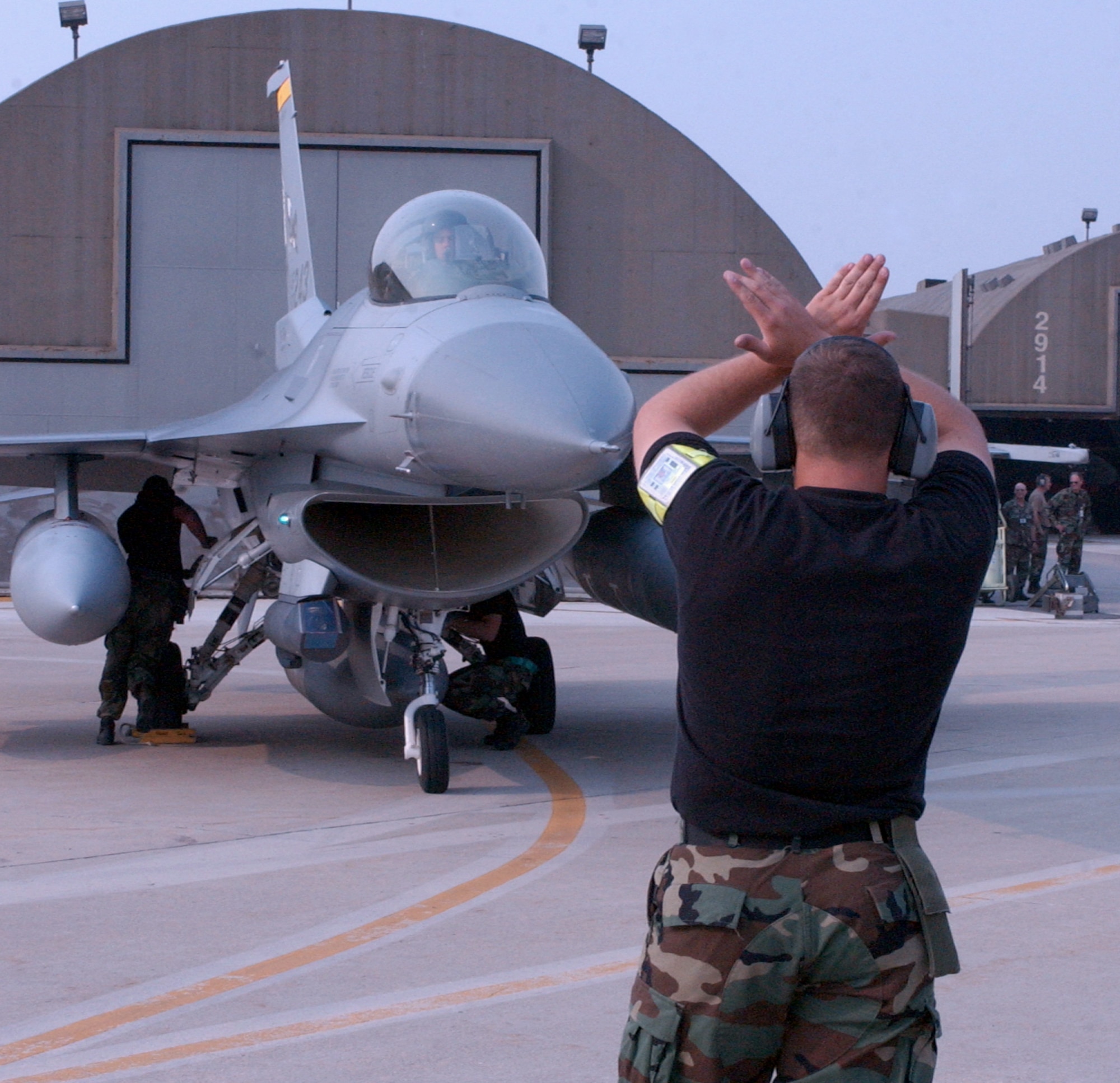 A crew chief guides an F-16 Fighting Falcon from the New Mexico Air National Guard's 150th Fighter Wing into place at Kunsan Air Base, South Korea. Elements of fighter wings from three Air National Guard units have deployed here in support of the air expeditionary force. (U.S. Air Force photo/Staff Sgt. Matt Schwartz) 
