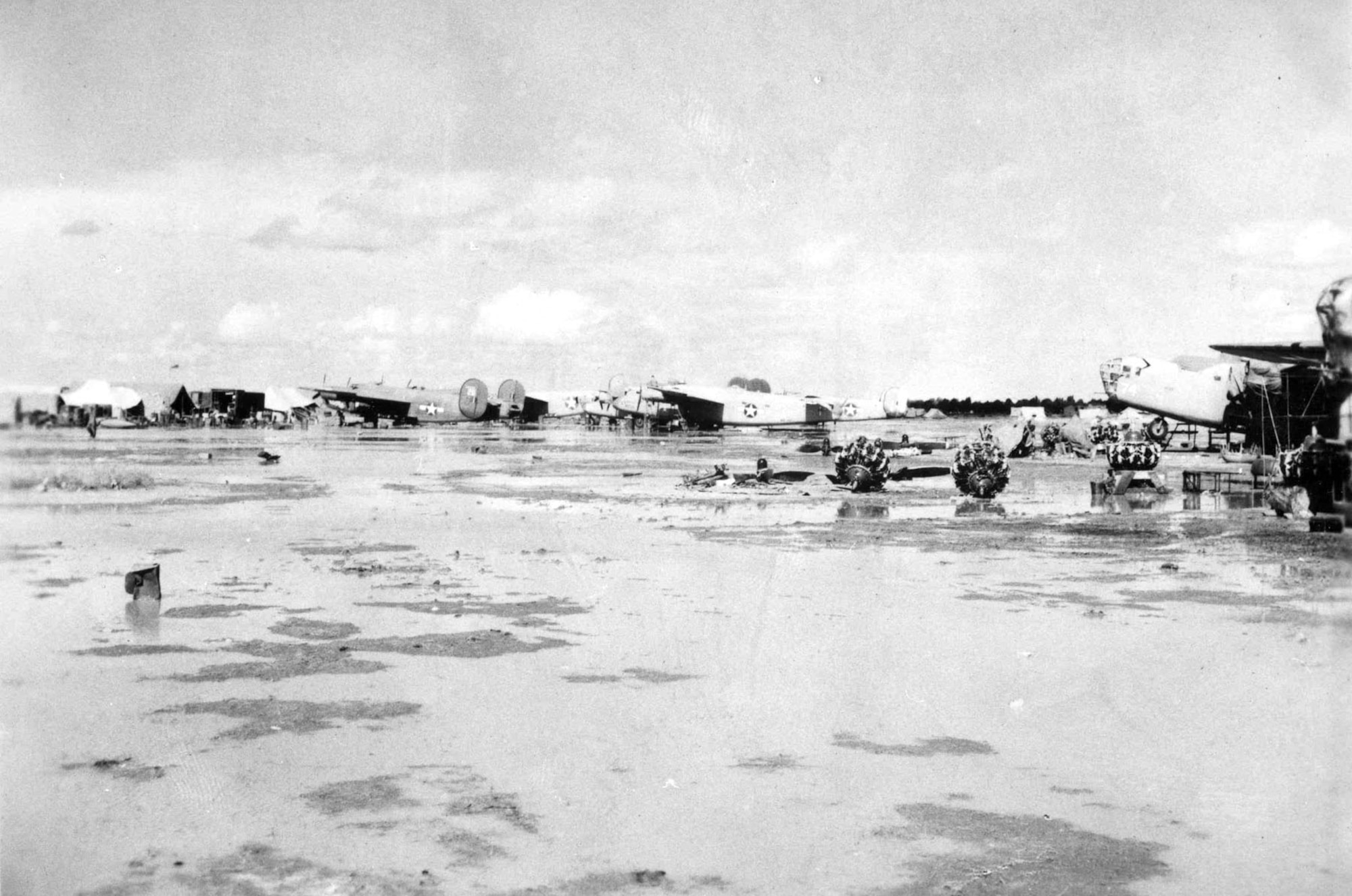 58th Service Squadron depot. Note the standing water and the engines laying on the ground. The Consolidated B-24D "Strawberry Bitch" is in the center of the photo (with vertical stabilizers removed). (U.S. Air Force photo)