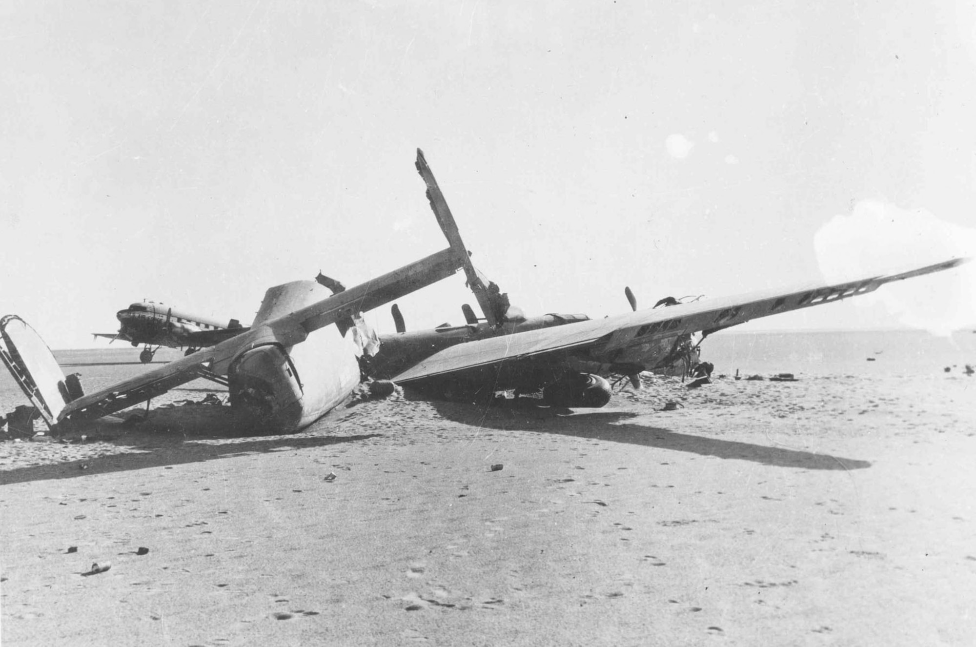 Tail view of the crashed Consolidated B-24D "Lady Be Good." Note the C-47 recovery aircraft parked in the background. (U.S. Air Force photo)