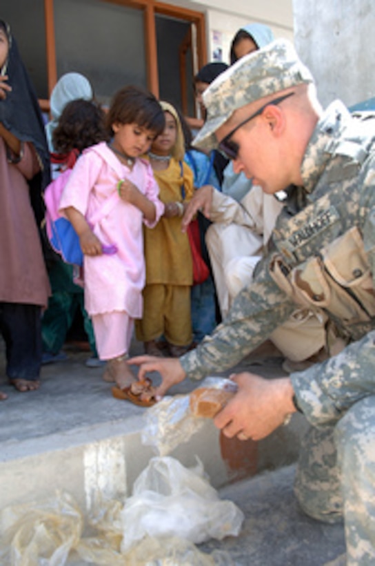 Army Maj. Roy Waldhoff helps an Afghan girl try on a new pair of sandals at the Shaheed Abdul Ahad Karazai Orphanage in Daman, Kandahar, Afghanistan, on May 29, 2006. The National Command Element and the Afghan National Army visited the orphanage to distribute donated school supplies, clothes, shoes, and food. Waldhoff is attached to Task Force Aegis J-37. 