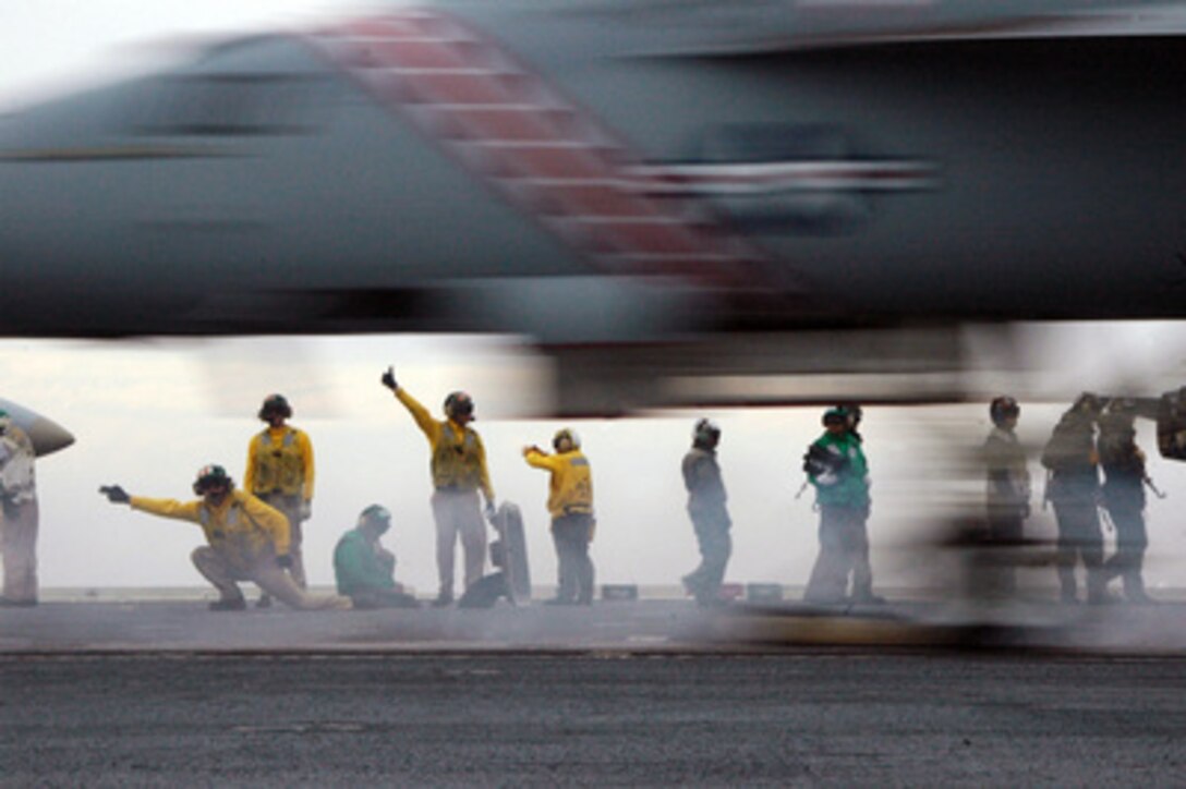 A U.S. Navy F/A-18F Super Hornet aircraft from Strike Fighter Squadron 102 hurtles past flight deck crewmen as it catapults from the aircraft carrier USS Kitty Hawk (CV 63) during carrier qualifications in the Pacific Ocean on May 30, 2006. Crews and aircraft from Carrier Air Wing 5 are conducting the carrier qualifications in preparation for an underway period. 