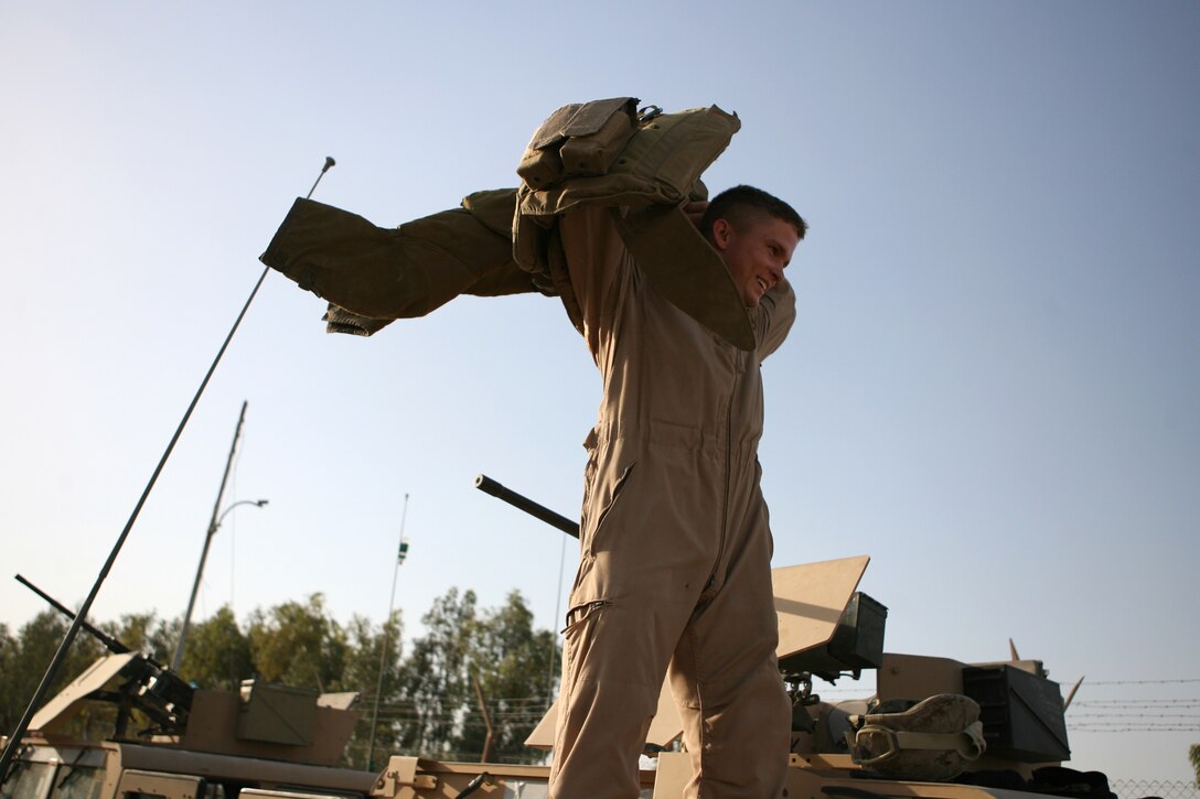 Standing atop a humvee, Lance Cpl. Josh Martin, a 19-year-old from St. Louis, Mo., throws his protective vest on in preparation of manning a machine gun June 2, 2006, as he and his fellow Marines provide security for a re-supply convoy in the Fallujah area.  Part of Combat Logistics Battalion 5, Security Company is responsible for making sure the battalion?s supply convoys get to their destination safely. The unit also provides security for explosive ordnance disposal teams and vehicle recovery missions.