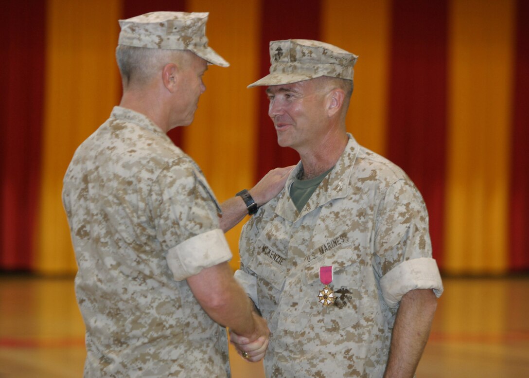 Lt. Gen. James F. Amos, Commanding General of II Marine Expeditionary Force, congratulates Col. Kenneth F. McKenzie upon recieving a Legion of Merit medal during the during the 22nd Marine Expeditionary Unit's change of command ceremony held in Goettge Memorial Field House June 2, 2006.  Col. McKenzie relinquished command to Col. Douglas Stilwell.