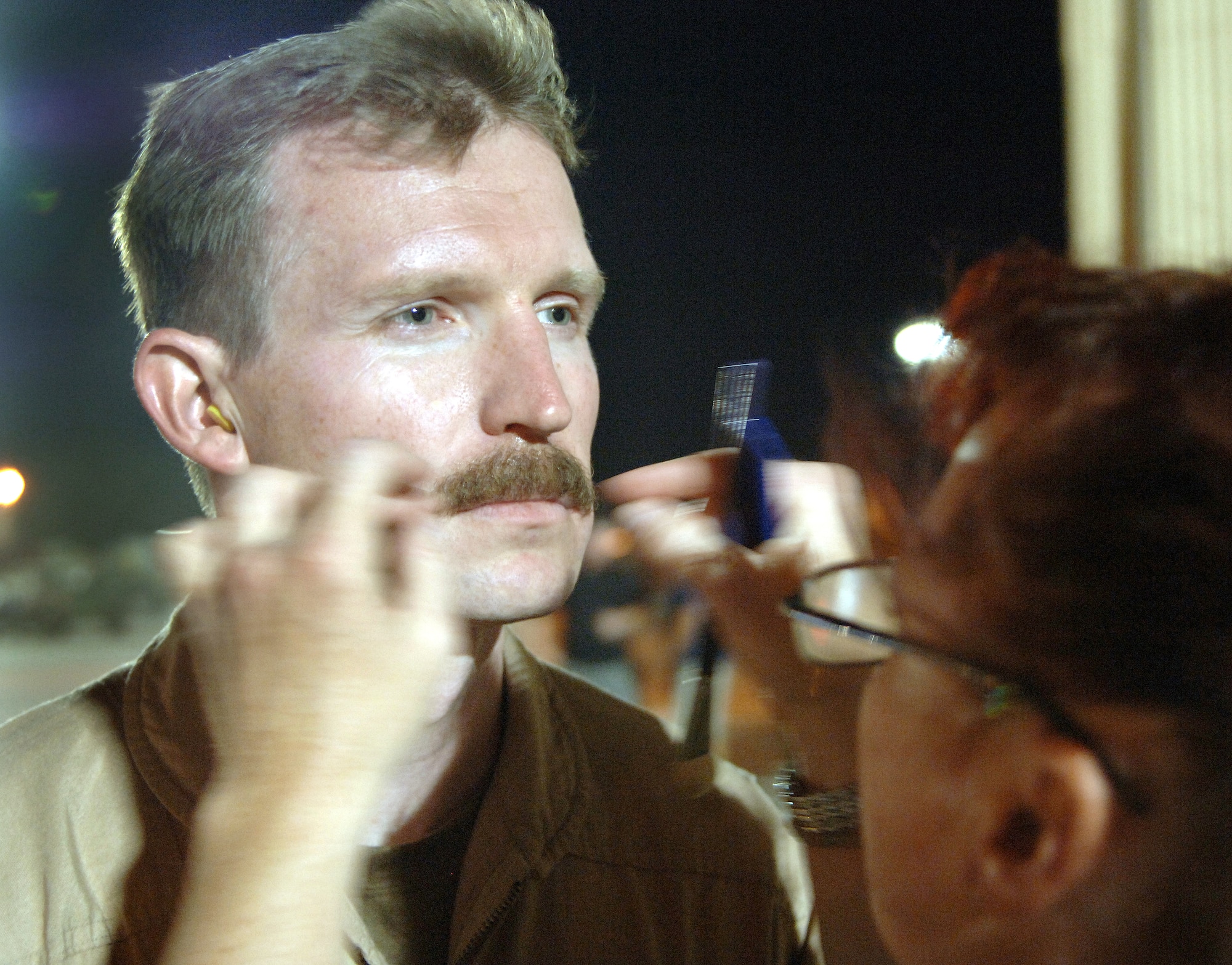 Makeup artist Robin Beauchesne glues a mustache on Capt. Brian Reece on the set of the movie "Transformers" at Holloman Air Force Base, N.M., on Wednesday,  May 31, 2006. The movie is scheduled for release in June 2007. Captain Reece is with the 58th Special Operations Wing at Kirtland AFB, N.M. (U.S. Air Force photo/Tech. Sgt. Larry A. Simmons)