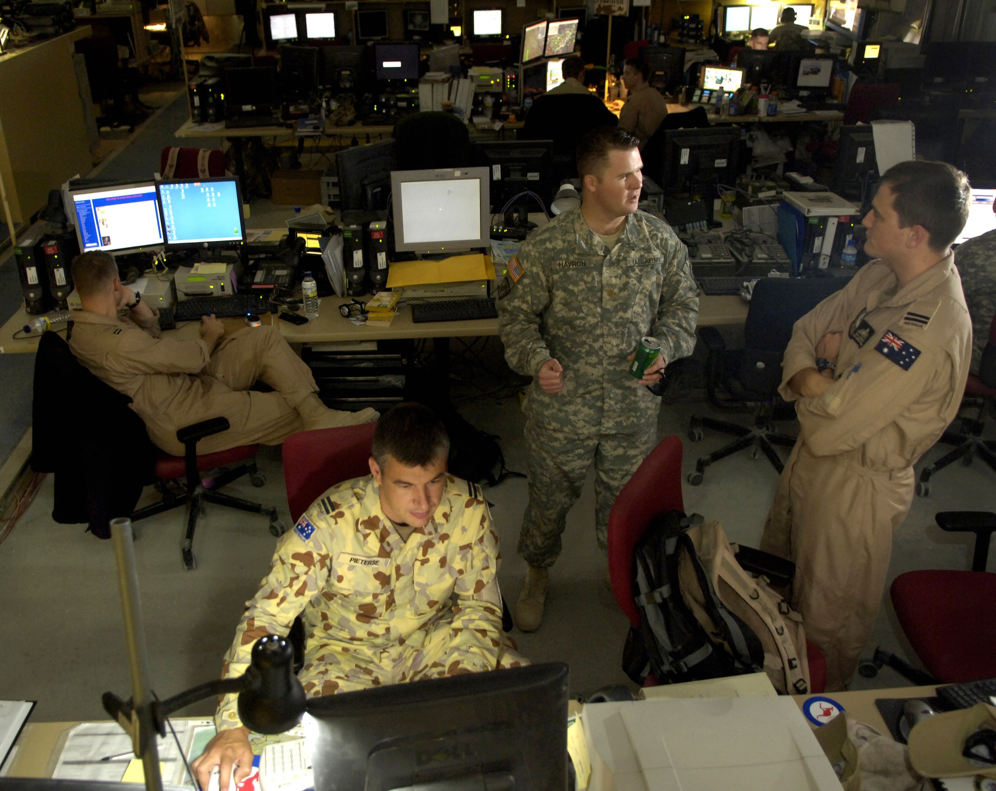 Flight Lt. Herman Pieterse works at his computer as Army Maj. Brandon Havron discusses battlefield coordination with Flight Lt. Ben Miedecke on Thursday, June 1, 2006, at the Combined Air Operations Center in Southwest Asia. The lieutenants are liaison officers for the Royal Australian Air Force; Major Havron is with the battlefield coordination detachment at the CAOC. (U.S. Air Force photo/Senior Airman Brian Ferguson) 