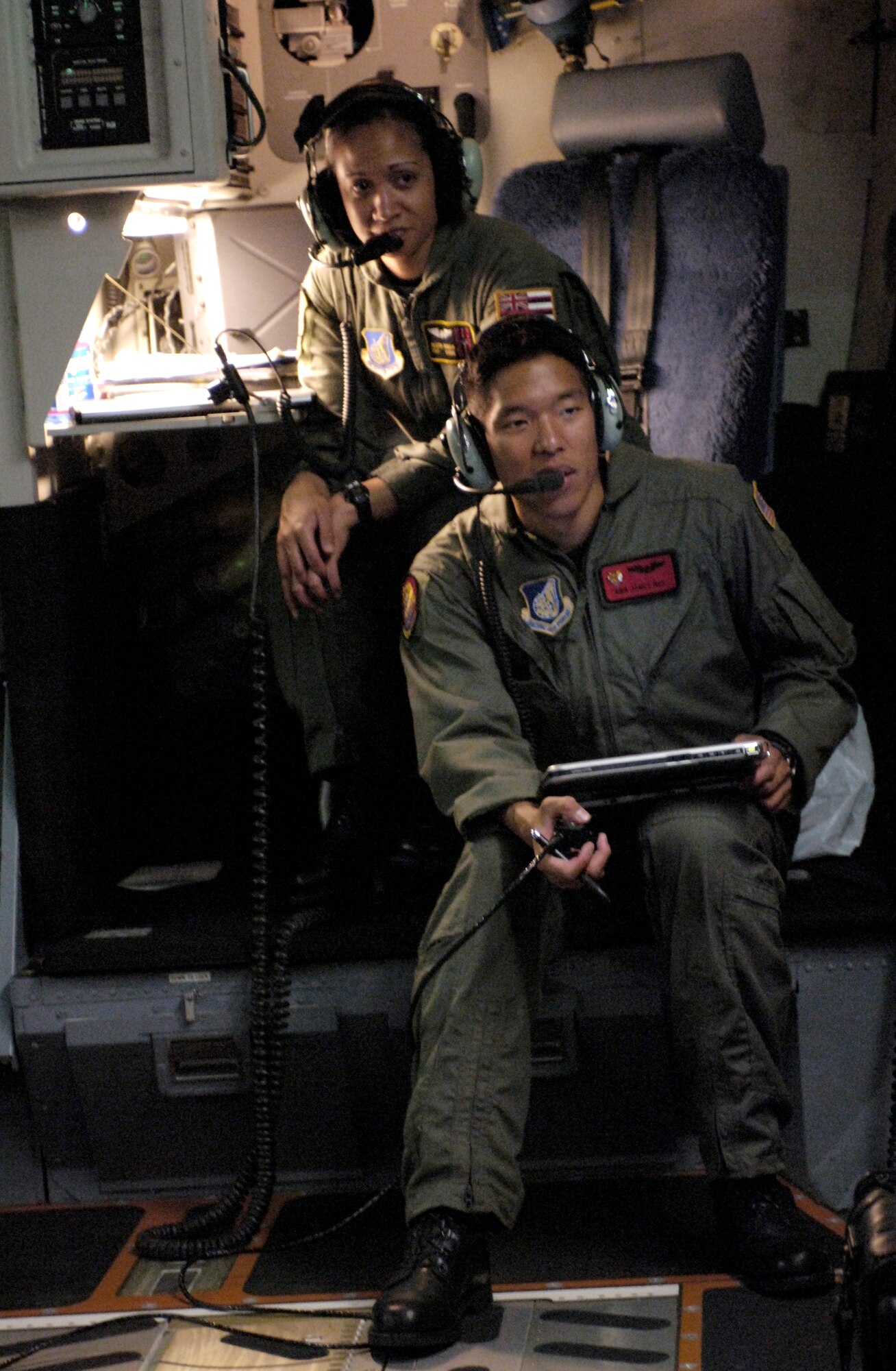 HICKAM AFB, Hawaii, (AFPN) - Airman James Ngo, 535th Airlift Squadron loadmaster, and Staff Sgt Joleen Manuia, 204th Airlift Squadron loadmaster use in-flight communication systems to answer questions from their instructor aboard a C-17 Globemaster III on May 27, 2006.  (U.S. Air Force photo by Tech Sgt. Shane A. Cuomo)