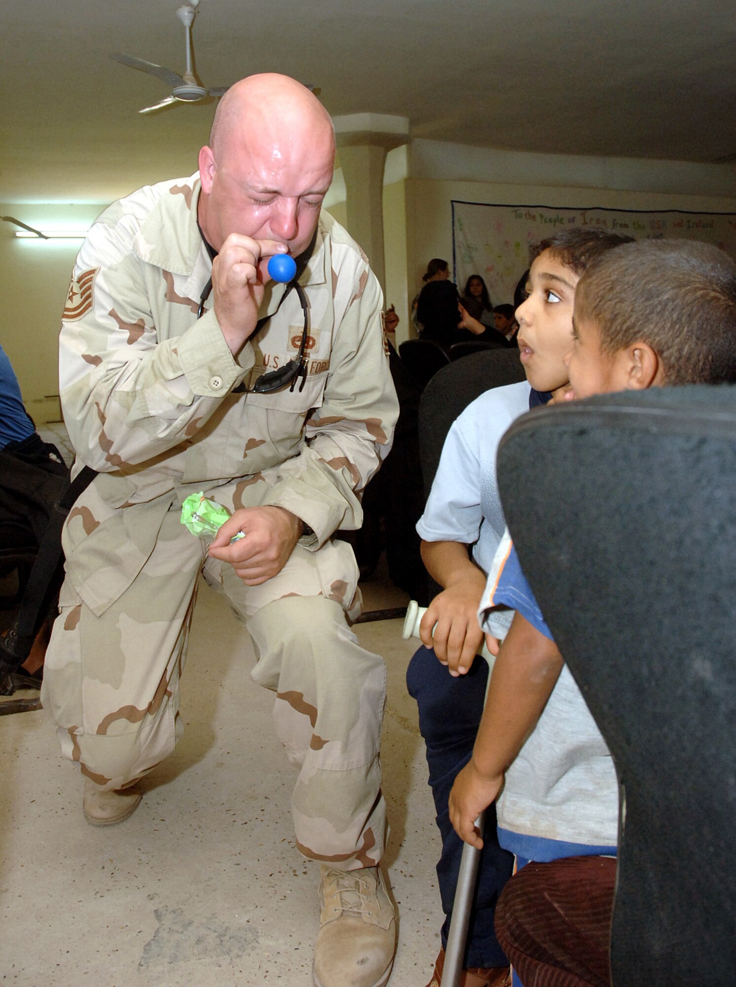 Tech. Sgt. John Carpenter blows up balloons for two Iraqi boys at the Army's Civil Military Operations Center at the Radwinya Palace Complex near Sather Air Base, Iraq, on Saturday, June 3, 2006. Sergeant Carpenter is with the Coalition Military Assistance Transition Team at New Al Muthana Iraqi air base, training Iraqi airmen. (U.S. Air Force photo/Staff Sgt. Bryan Bouchard) 
