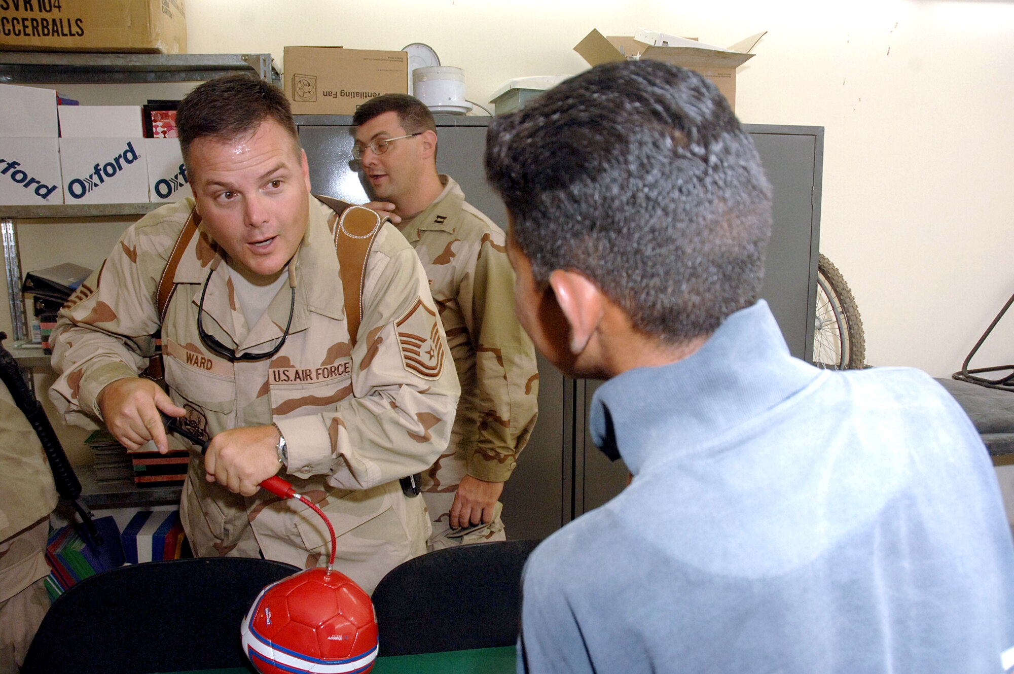 Master Sgt. Matt Ward tells an Iraqi boy that he can have the soccer ball as soon as he pumps it up. They were at the Army's Civil Military Operations Center at the Radwinya Palace Complex near Sather Air Base, Iraq, on Saturday, June 3, 2006.  The complex provides medical care and other services to Iraqi villagers. Sergeant Ward and several other Airmen volunteer at the facility. Sergeant Ward is assigned to the 447th Air Expeditionary Group and is deployed from Eglin Air Force Base, Fla. (U.S. Air Force photo/Staff Sgt. Bryan Bouchard)