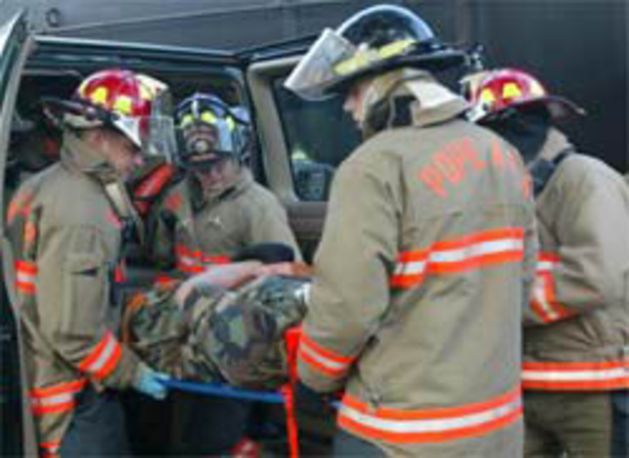 Firefighters carry an "injured" Airman away from the scene of the "accident" May 24 as part of a base exercise. The event involved wing agencies across the base including the medical group, civil engineering squadron, disaster control group and many others