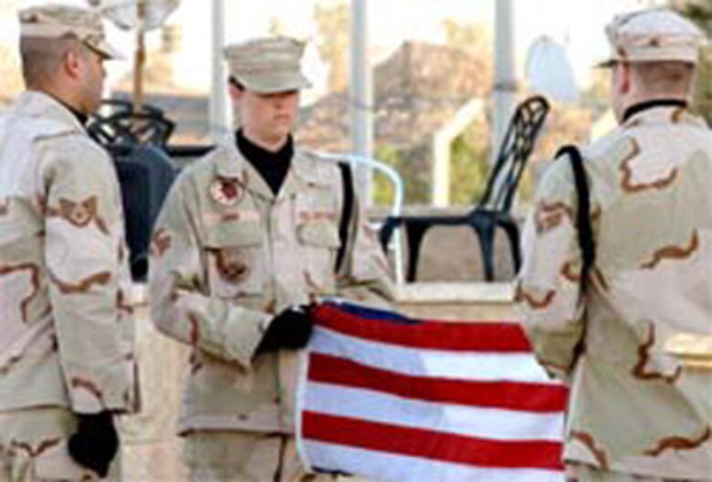 An honor guard from the 447th Air Expeditionary Group folds the flag during the Memorial Day retreat ceremony at Sather AB, Iraq. From left are Staff Sgt. Jimmy Roman, deployed from Pope, and Senior Airmen Peyton John and Dennis Maser. The 447th AEG operates the primary aerial port for transient military aircraft entering and exiting Iraq. The base is named in honor of Staff Sgt. Scott Sather, a combat controller assigned to Pope's 24th Special Tactics Squadron who was killed in combat in Iraq on April 8, 2003.
