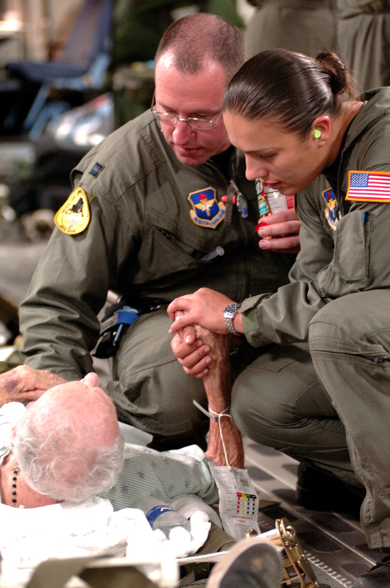 Capt. Mike Dixon and Staff Sgt. Lina Gamez provide a hand to hold and reassuring words to an elderly patient during the evacuation for Hurricane Katrina on Sept. 1, 2005, in New Orleans. Captain Dixon is an intensive care nurse and Sergeant Gamez is a respiratory therapist with the 59th Medical Wing at Lackland Air Force Base, Texas. (U.S. Air Force photo/Master Sgt. Lance Cheung)
