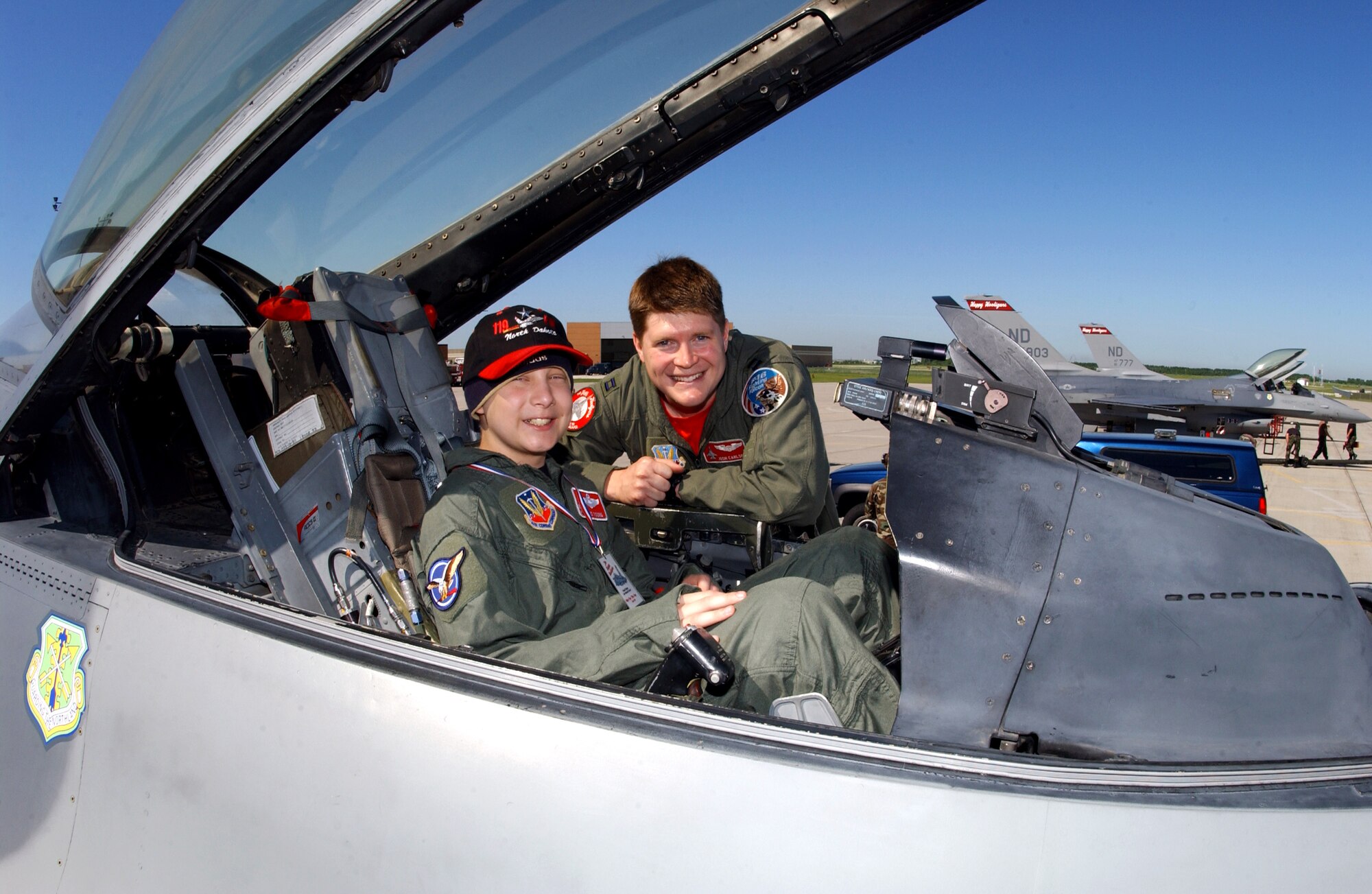 Capt. Joshua Carlson helps "pilot for a day" Kris Young into the cockpit of an F-16 Fighting Falcon at the Air National Guard's 119th Fighter Wing in Fargo, N.D., on Friday, June 2, 2006. The pilot for a day program gives children with serious health conditions a day away from medical tests and treatments. Thirteen-year-old Kris, from West Fargo, N.D., has Burkitt's lymphoma, a type of cancer. He has two uncles in the Air Force, one in the Marines, one in the Coast Guard and one in the Army. Captain Carlson is with the 178th Fighter Squadron. (U.S. Air Force photo/Senior Master Sgt. David H. Lipp) 