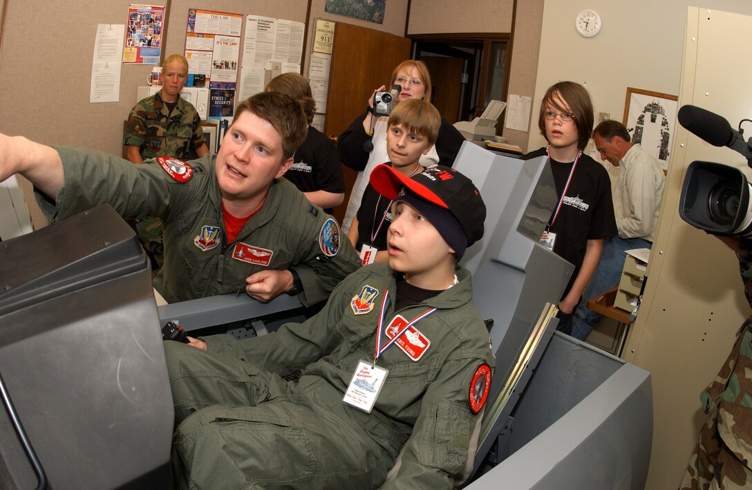 Capt. Joshua Carlson helps "pilot for a day" Kris Young operate an F-16 Fighting Falcon flight simulator at the Air National Guard's 119th Fighter Wing in Fargo, N.D., on Friday, June 2, 2006. The pilot for a day program gives children with serious health conditions a day away from medical tests and treatments. Thirteen-year-old Kris, from West Fargo, N.D., has Burkitt's lymphoma, a type of cancer. He has two uncles in the Air Force, one in the Marines, one in the Coast Guard and one in the Army. Captain Carlson is with the 178th Fighter Squadron. (U.S. Air Force photo/Senior Master Sgt. David H. Lipp)