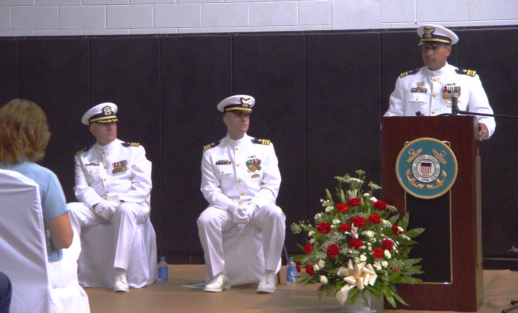 Incoming commanding officer Lt. Cmdr. Jonathan Theel, seated-right, listens to outgoing commanding officer Lt. Cmdr. Carlos Mercado during the Maritime Safety and Security Team 911-14 change of command ceremony on May 26.  Capt Bradley Jacobs, Chief of Response Enforcement for U.S. Coast Guard Atlantic Area, presided over the ceremony (Air Force photo by Lisa Macias).