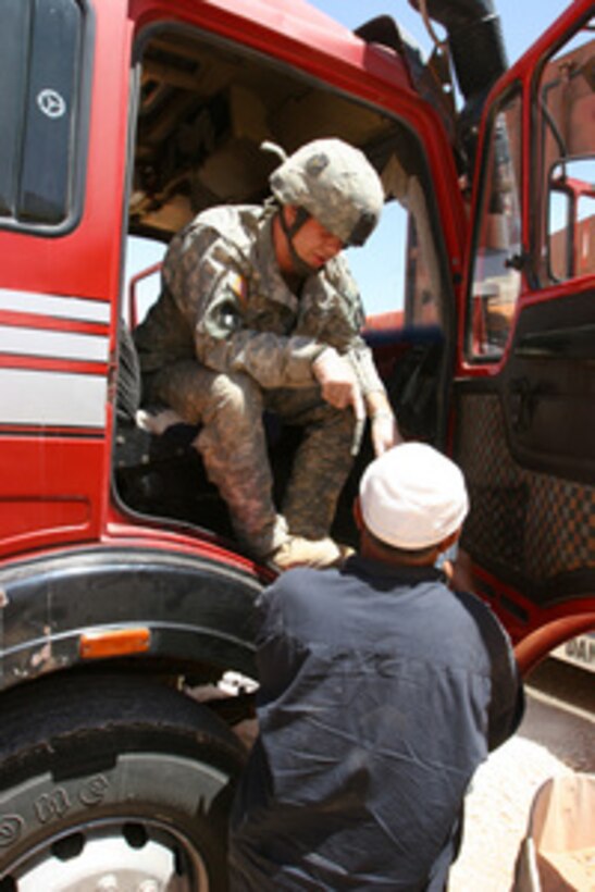 U.S. Army Pfc. Justin Hass sits in the cab of a truck as he questions a driver at Al Asad Air Base, Iraq, on May 25, 2006, before continuing on a three-day convoy to Jordan. Hass is attached to Charlie Company, 2nd Battalion, 135th Infantry Regiment and is deployed to support I Marine Expeditionary Force (Forward). 