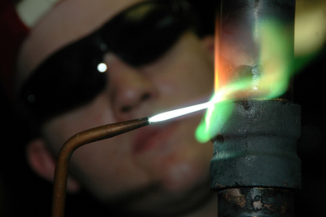 U.S. Navy Fireman Bob Chambers uses a brazing torch to weld a copper-nickel pipe on board the aircraft carrier USS Kitty Hawk (CV 63) as the ship operates in the Pacific Ocean on May 28, 2006. Chambers is a Navy hull maintenance technician. 
