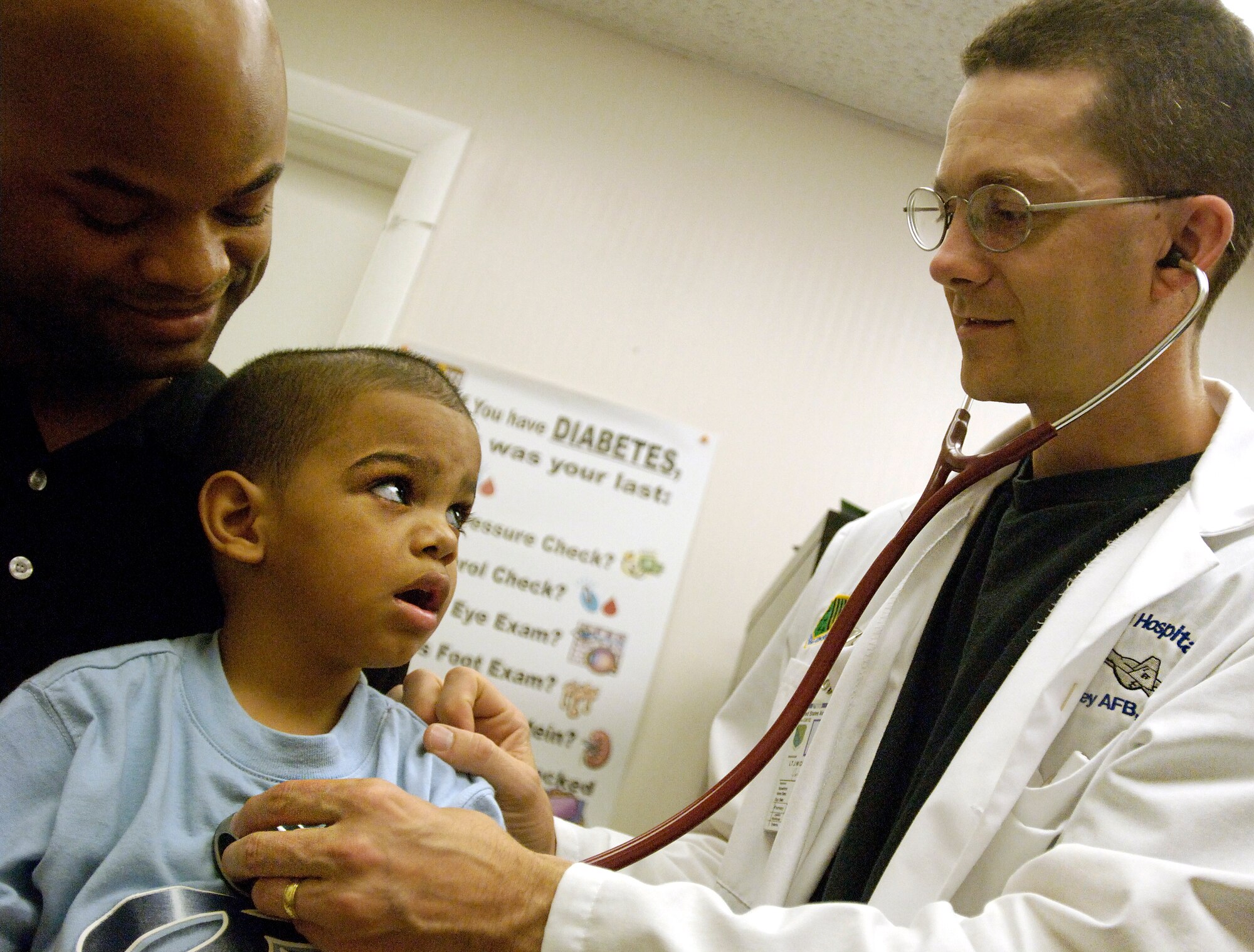 Staff Sgt. Richard Stowe Jr., 83rd Communications Squadron,  holds his son, Richard III, while 1st Lt. Jason Collins, 1st Medical Operations Squadron, checks him out. (Photo by Senior  Airman Austin Knox)
