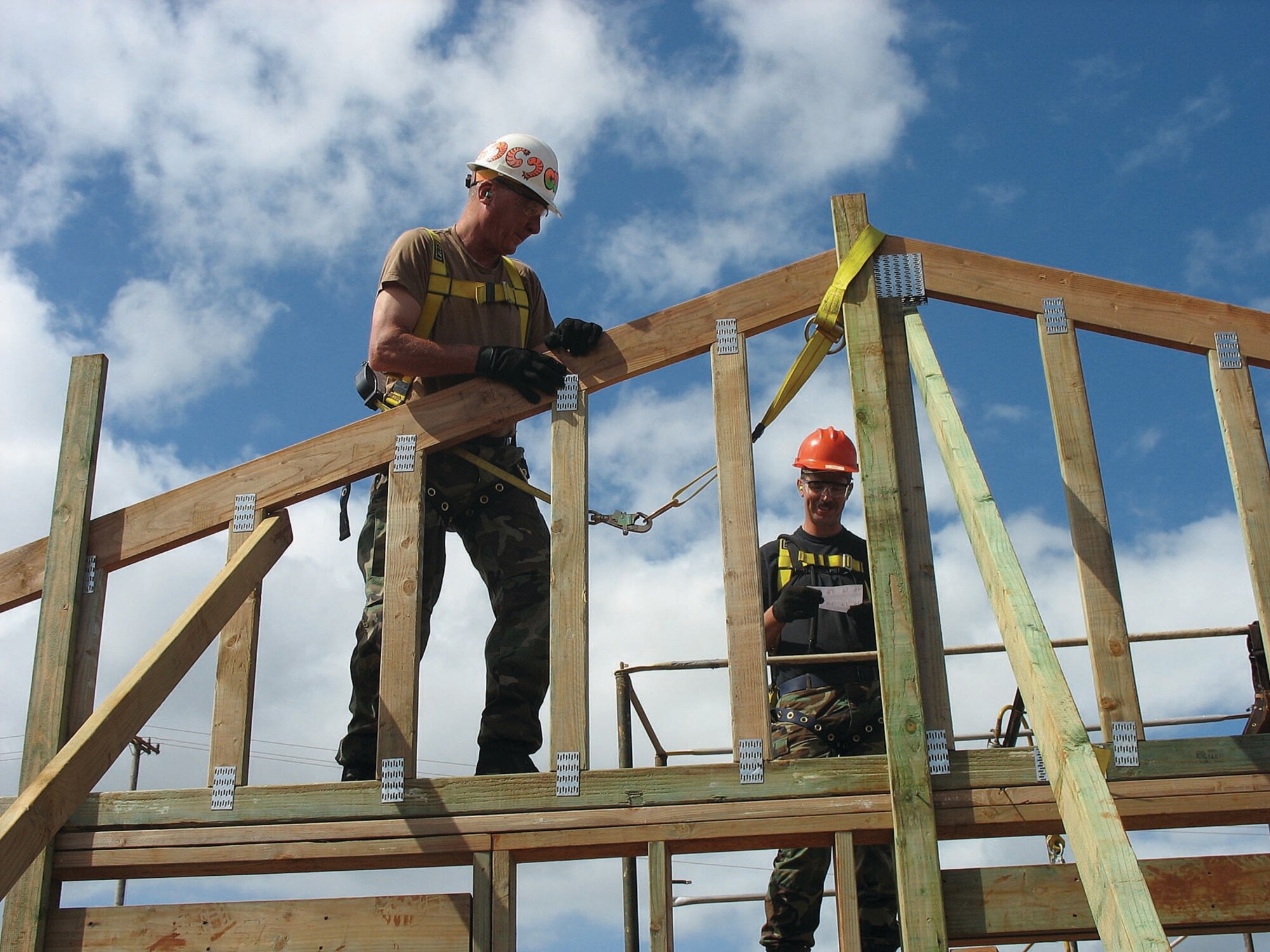 Senior Master Sgt. John Lough, Heavy Equipment Operator, and Tech. Sgt. Steve Tracey, Power Production, work on framing one of the living structures at the “Aloha Gardens’ compound.