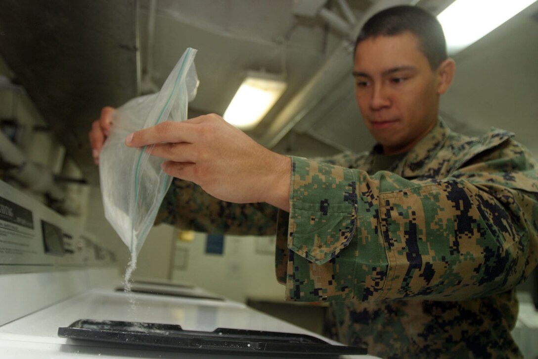 ABOARD THE USS BOXER,  (June 10, 2006) -- Sgt. Martin T. Bustamante, videographer for the 15th Marine Expeditionary Unit, pours laundry soap into a washing machine aboard the USS Boxer during the units 1st at sea training exercise. Doing laundry is one of many tasks that may be easy to do while ashore but can become difficult to do while aboard a ship with more than 2,000 service members.