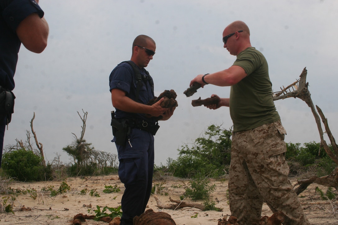 Sgt. Steven Vereen, right, an explosive ordnance disposal technician, works with Coast Guard Petty Officer 2nd Class Daniel Ipock to collect unexploded ordnance on Wood Island.
