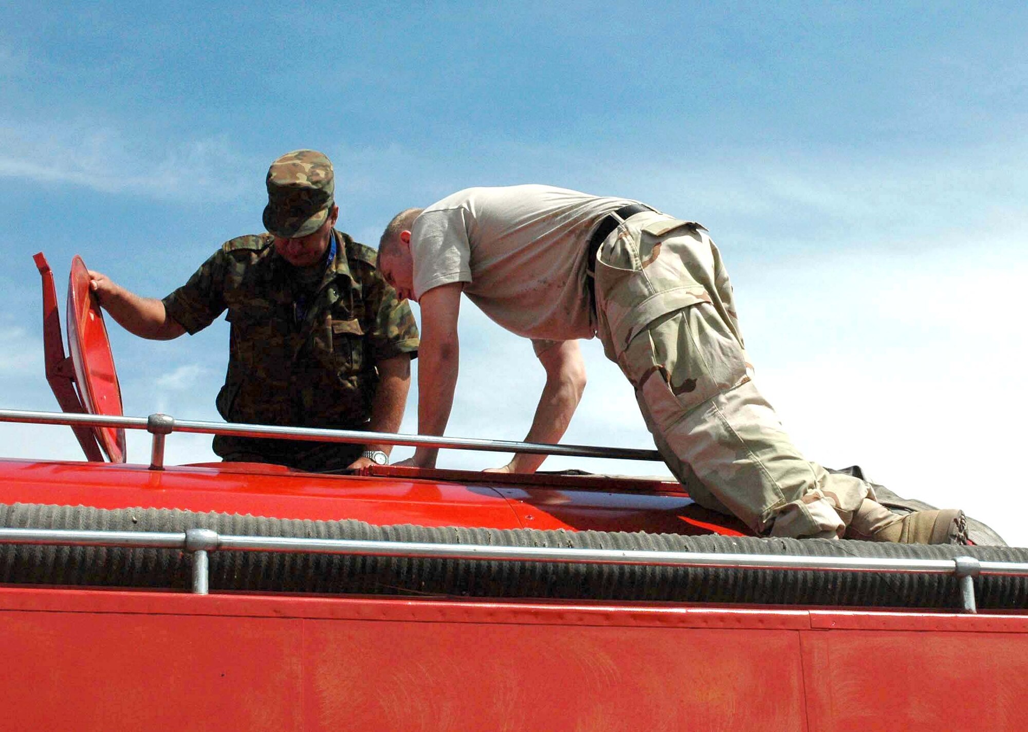 Airman 1st Class Matthew Pfister and a firefighter from the Manas International Airport inspect a fire engine. The 376th Expeditionary Civil Engineer Squadron's fire department and Manas International Airport emergency response team held a joint training exercise June 6 to 7. Airman Pfister is deployed from Moody Air Force Base, Ga., and is assigned to the 376th ECES. (U.S. Air Force photo/Staff Sgt. Candy Knight) 

