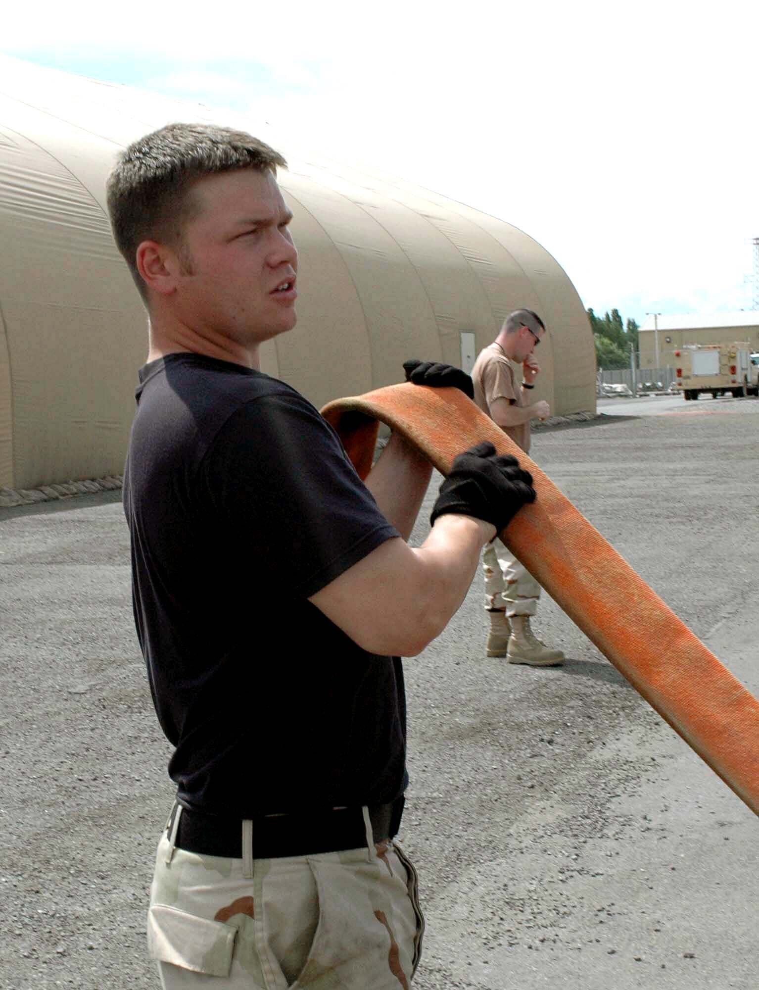 Senior Airman Michael Deaton prepares to hook a fire hose to a firefighting vehicle at Manas Air Base, Kyrgyzstan, on Wednesday, June 7, 2006. The 376th Expeditionary Civil Engineer Squadron's fire department and Manas International Airport emergency response team held a joint training exercise June 6 to 7. Airman Deaton is deployed from Moody Air Force Base, Ga., and is assigned to the 376th ECES. (U.S. Air Force photo/Staff Sgt. Candy Knight)