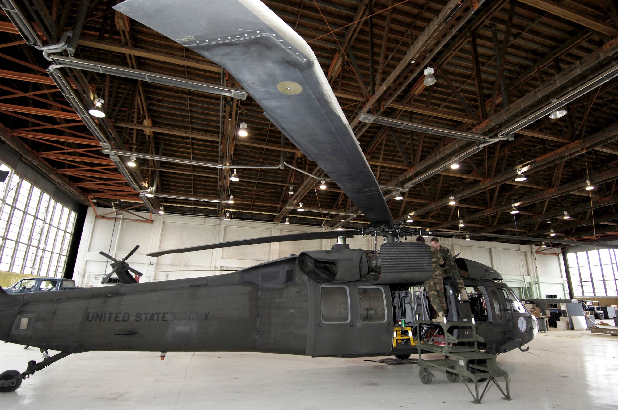 Two members of the Army National Guard's Aviation Support Facility #2 unit install an engine cover on a UH-60A Blackhawk helicopter in preparation for the move. The unit is relocating their helicopters and support equipment from Geiger Air Field to Fairchild's Hangar 1001.