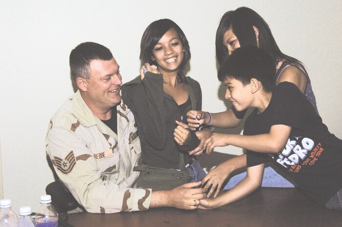Anne Rebbe (middle) fights to keep the text message she just received private as her brother, Andrew, and sister, Ashley, try to pry the cell phone from her hand. Watching the sibling rivalry is their dad, Tech Sgt. Freidrick Rebbe, who was waiting for his plane to depart Nellis Air Force Base June 2. He is one of 70 members of the 99th Security Forces Squadron who deployed to Iraq.