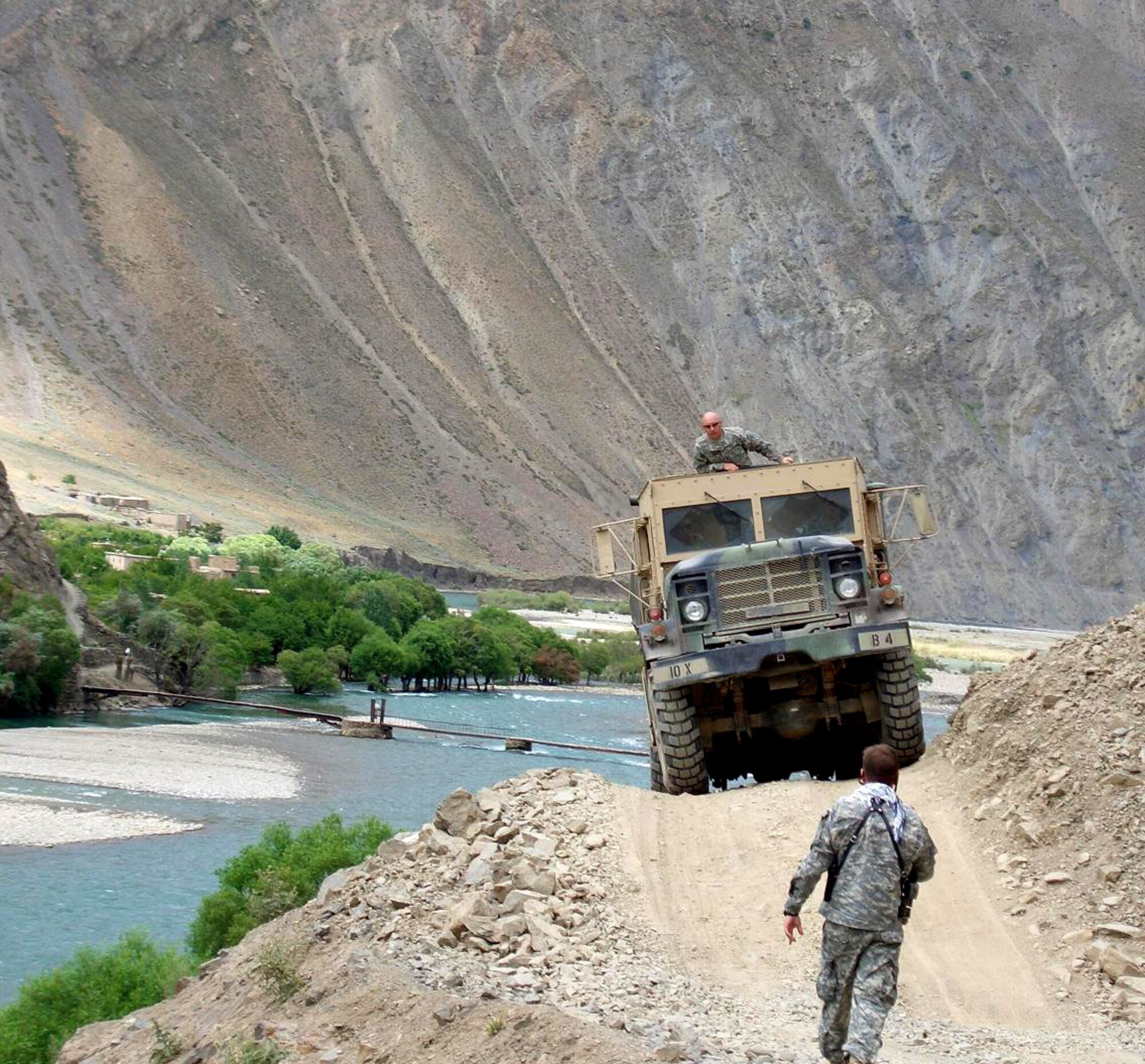 A five-ton, six-wheel drive truck loaded with humanitarian assistance supplies makes its way over a narrow road in the Panjshir Province, Afghanistan, on Monday, June 12. With a ground guide and spotter in the truck's turret, the multi-service supply convoy delivered supplies to the village of Dara. (Courtesy photo/Marine Col. Steve Hasty)