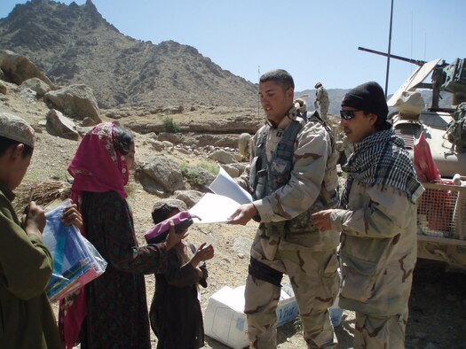 Capt. Kevin Tuttle hands out art suplies and toys to welcoming village children during a recent Village Medical Outreach Operation in Sal Kalay, Afghanistan.  The VMO travels with two doctors, one physician's assistant and five medical technicians who provide medical attention to those with complaints of muscle aches to more grave matters such as liver failure.  Captain Tuttle is a Qalat Provincial Reconstruction Team Information Officer deployed from the 45th Space Wing at Patric Air Force Base, Fl. (U.S. Air Force Photo by Master Sgt. Michael Morris)