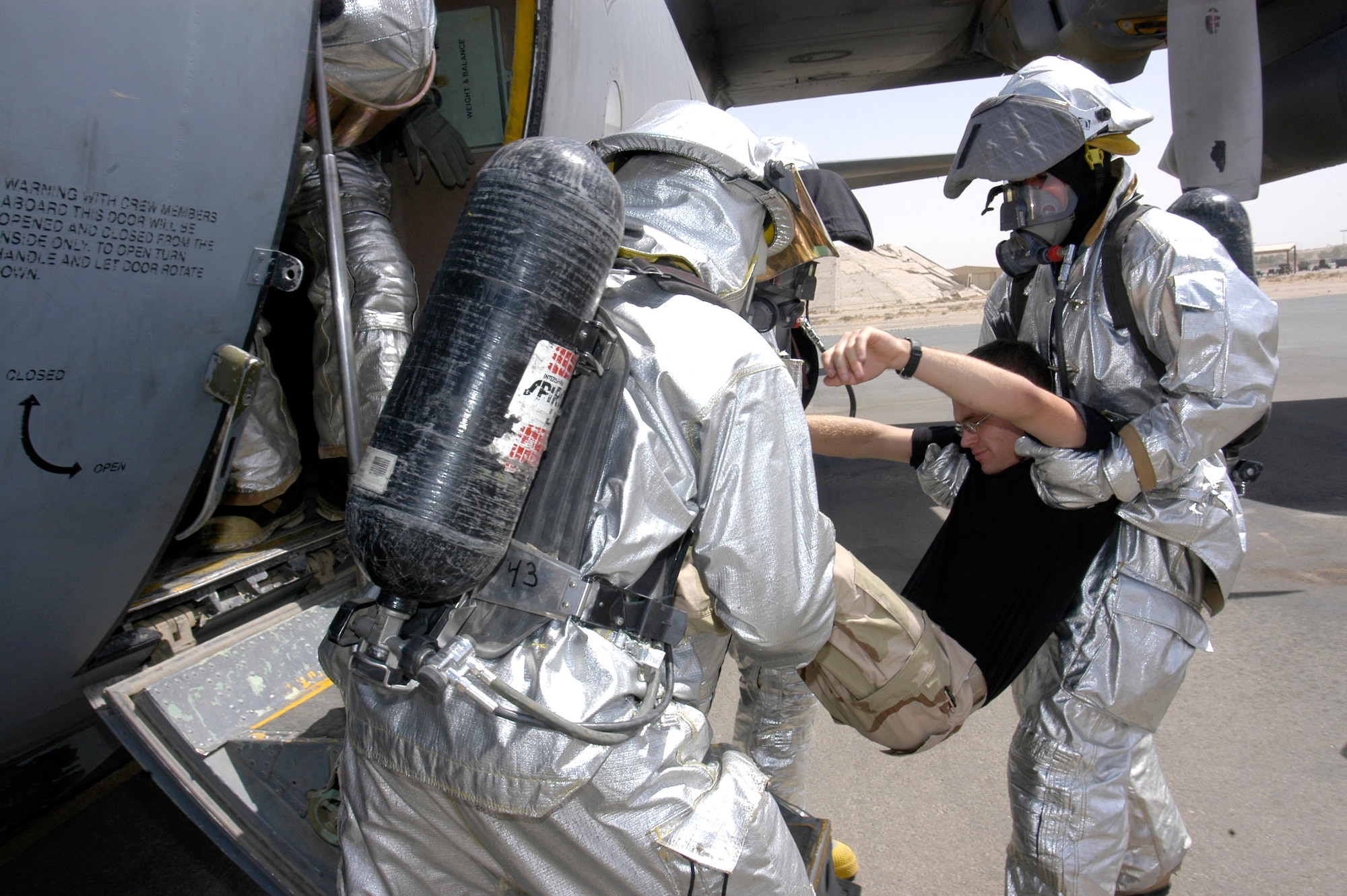 Firefighters evacuate a simulated patient during C-130 Hercules egress training at a deployed location in Southwest Asia on Wednesday, June 14. The Airmen are firefighters assigned to the 386th Expeditionary Civil Engineer Squadron. (U.S. Air Force photo/Staff Sgt. Ryan Hansen)
