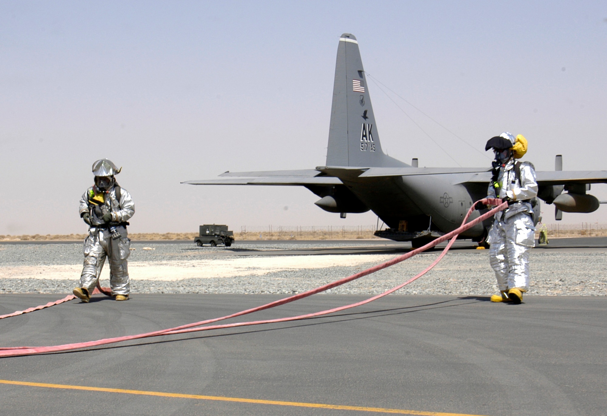 Staff Sgt. Jason Glefke (left) and Airman 1st Class Donalyvn Smith unreel a water hose during C-130 Hercules egress training at a deployed location in Southwest Asia on Wednesday, June 14. Sergeant Glefke is deployed from Robins Air Force Base, Ga., and Airman Smith is from Shaw AFB, S.C. Both are assigned to the 386th Expeditionary Civil Engineer Squadron. (U.S. Air Force photo/Staff Sgt. Ryan Hansen) 
