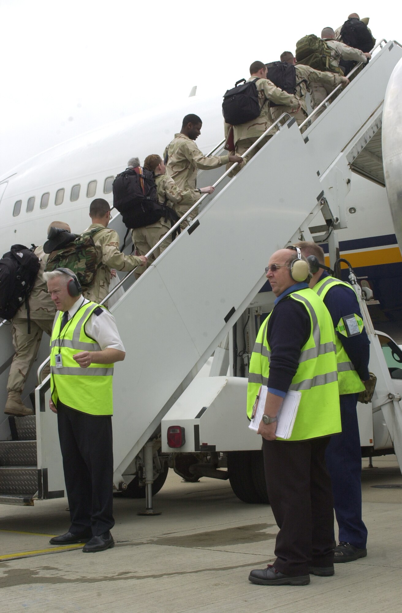 Passenger service personnel from the 727th Air Mobility Squadron passenger terminal at RAF Mildenhall, wearing fluorescent jackets, direct members of the 48th Security Forces Squadron to safely board an aircraft June 2. In addition to working with deploying members, the passenger service agents also work with travellers flying space-available, and on commercial rotators. (U.S. Air Force photo by Karen Abeyasekere)
