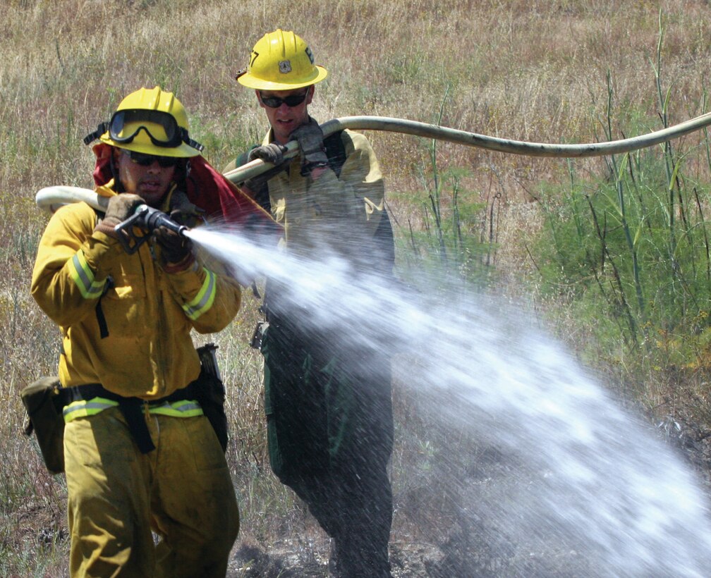 Larry Rivas, a fire fighter with Califorina Department of Forestry and Fire Protection, attacks a controlled fire on base with a 150 gallon-per-minute hose Tuesday. Rivas leads his team, engine 3386, for an all-day training evolution to learn how to properly extingush wild-land fires.