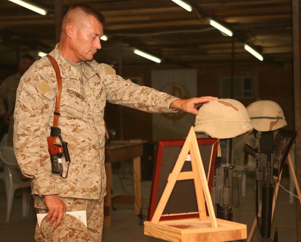 In a moment of silence, Col. David M. Richtsmeier, commanding officer of 1st Marine Logistics Group (FWD), honors two fallen members of Naval Mobile Construction Battalion 25 during a memorial service held at the base chapel June 14, 2006. Members of the ?Seabee Family,? Petty Officer 1st Class Gary T. Rovinski, an equipment operator, and Petty Officer 2nd Class Jaime S. Jaenke, a corpsman, were killed June 5, 2006 by an improvised explosive device while their unit was convoying in the Al Anbar Province. A native of Roseville, Ill., Rovinksi is survived by his wife Jennifer and his two daughters, Cecilia, 13, and Michaela, 10. Jaenke, a native of Iowa Falls, Iowa, is survived by her parents Susan and Larry, and her daughter, Kayla, 9.