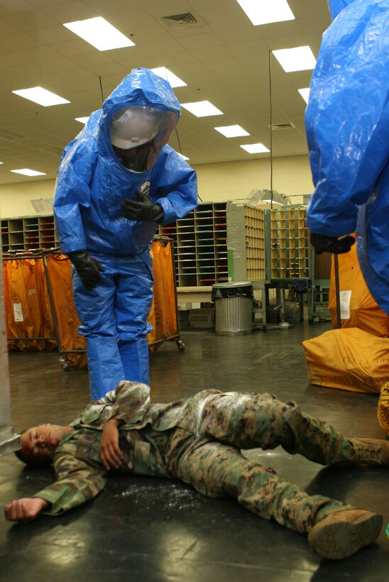 Cpl. Damien D. McGlotten, chemical, biological, radiological, nuclear and high yield explosives Marine, plays ?dead? in the base post office during anti-terrorism exercise Urgent Reponse 2006, while firefighters assess the situation. McGlotten and other Marines role play in the initial scenario, which includes a suspicious package leaking powder at the postal facility.