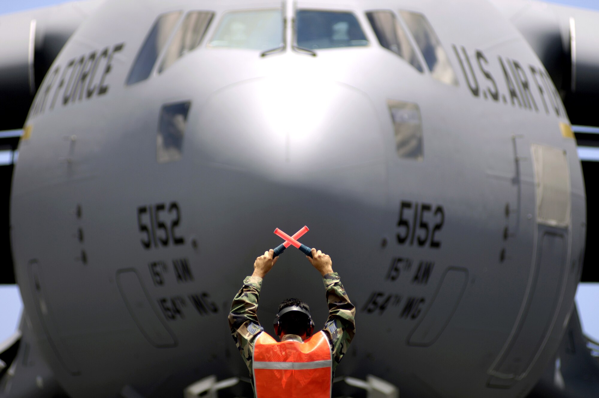 Tech. Sgt. Ronald Timbreza marshals a C-17 Globemaster III to its parking spot at Hickam Air Force Base, Hawaii, on Wednesday, June 14. The "Spirit of 'Go for Broke'" is named in honor of the 442nd Regimental Combat Team. The 442nd, comprised of 3,800 Japanese Americans, fought with distinction during World War II in North Africa and Europe, becoming one of the most highly decorated units in the history of the U.S. military. (U.S. Air Force photo/Tech. Sgt. Shane A. Cuomo)