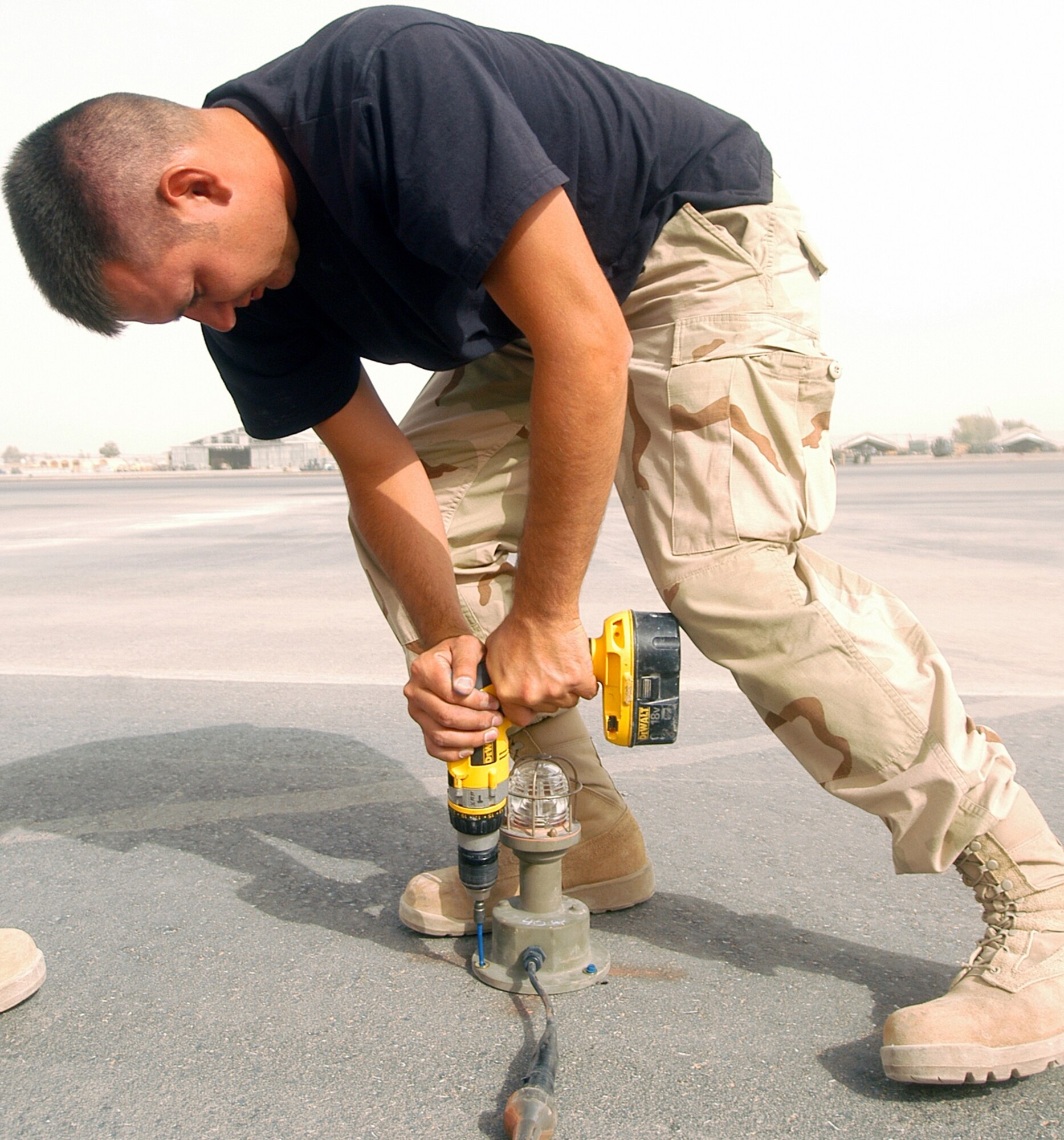 Senior Airman Joshua Williams, an electrician with the 1st Expeditionary REDHORSE Group, fastens a runway light at Kandahar Airfield, Afghanistan, June 4.  Airman Williams is deployed for Operation Enduring Freedom from the 819th REDHORSE Squadron at Malmstrom Air Force Base, Mont.  He and his fellow combat engineers helped keep flying operations going at Kandahar by installing an emergency airfield lighting system.  (US Air Force photo/Maj. David Kurle)