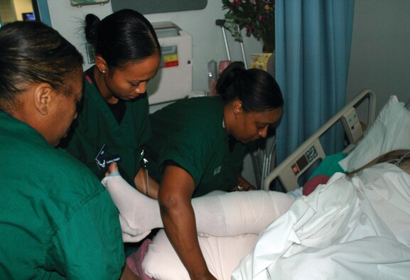 Staff Sgt. Dina Cooper (left) and Master Sgt. Aunshelle White (right), 917th Medical Squadron services attendants, train a pipeline student (middle) to put an anti-embolism stocking on a patient’s leg after knee surgery. Members of the 917 MDS deployed to the 10th Medical Group, Air Force Academy, Colorado Springs, Colo., May 27 - June 10.  (Photo by Mrs. Betty Stephens)