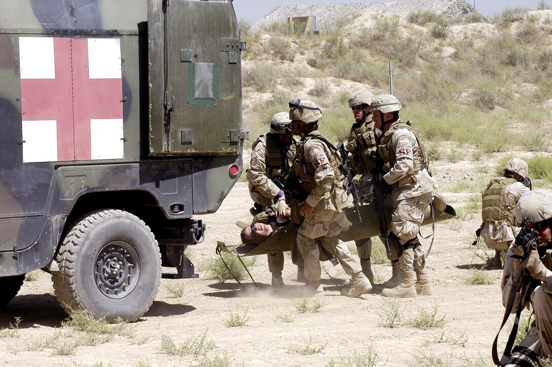 Airmen from the 455th Expeditionary Security Forces Squadron load a "wounded patient" into an ambulance during a combat lifesaver exercise at Bagram Air Base, Afghanistan, on Thursday, June 15, while other Airmen guard against hostile forces. (U.S. Air Force photo/Maj. David Kurle)