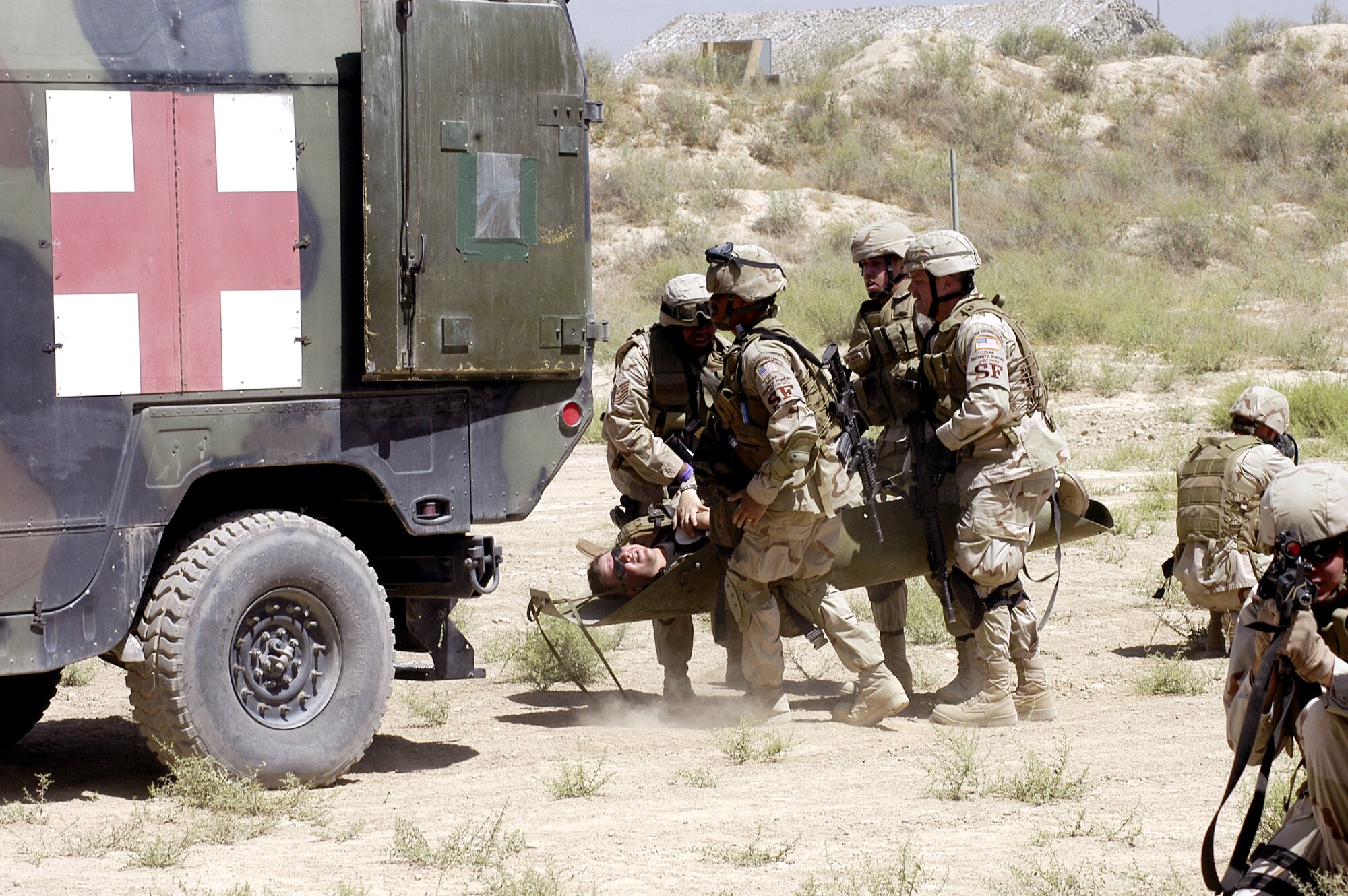 Airmen from the 455th Expeditionary Security Forces Squadron load a "wounded patient" into an ambulance during a combat lifesaver exercise at Bagram Air Base, Afghanistan, on Thursday, June 15, while other Airmen guard against hostile forces. (U.S. Air Force photo/Maj. David Kurle)
