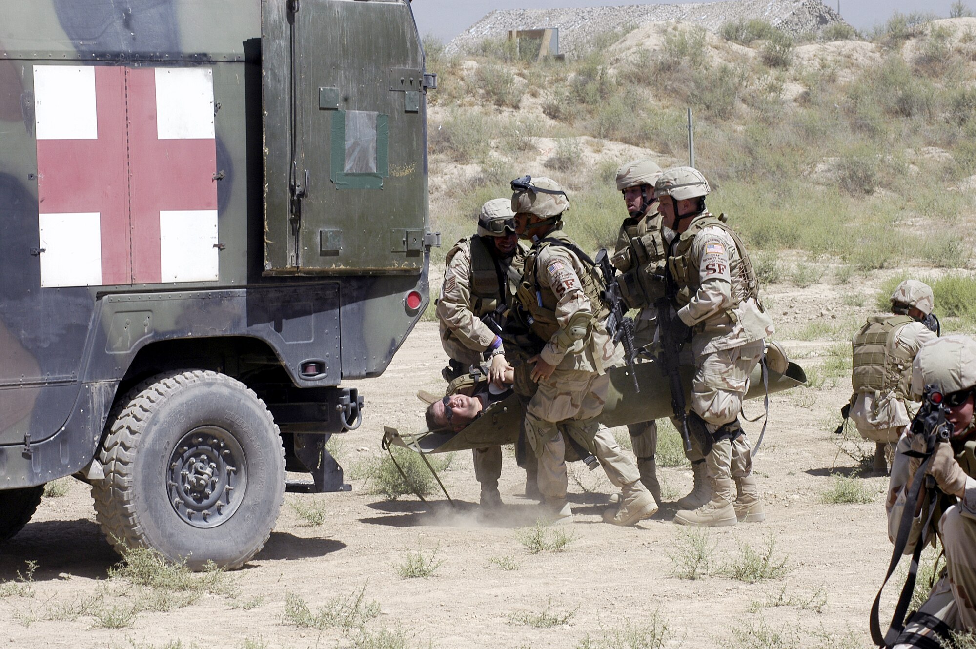 Airmen from the 455th Expeditionary Security Forces Squadron load a simulated wounded comrade into an ambulance during a combat life saver exercise at Bagram Airfield, Afghanistan, June 15, while other security forces guard against hostile forces.  (US Air Force photo/Maj. David Kurle)