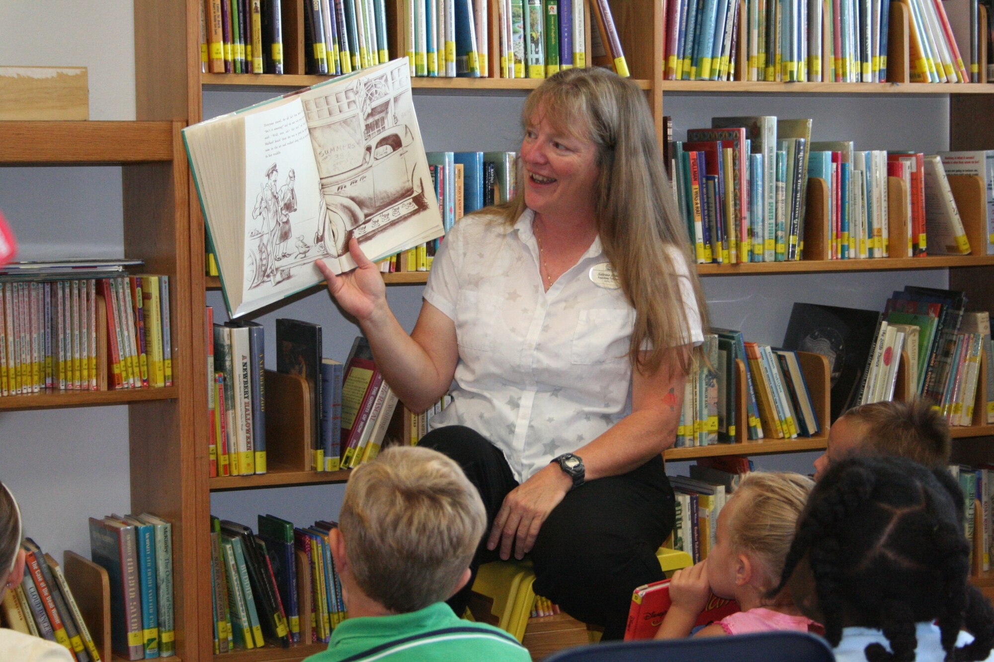 Sabrina Honda (center), the base library's program coordinator, reads a book to children as part of the library's summer reading hour.