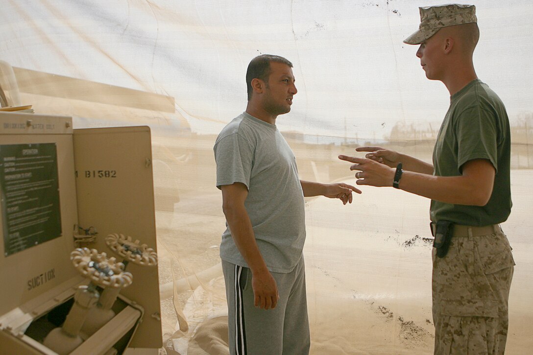 The language barrier is a tricky obstacle for Lance Cpl. Perry R. Schultz, a 20-year-old native of Sacramento, Calif., as he interacts with Iraqi contractors June 18, 2006 while working at the reverse osmosis water purification unit at Blue Diamond just outside of Ramadi. Shultz and two other Marines here utilize the system to produce 15,000 to 18,000 gallons of cleaned, purified and chlorinated water here every day for Iraqi Security Forces. Without the water, the ISF would be severely limited in their ability to prepare food, shower and otherwise survive as they conduct missions in the region.