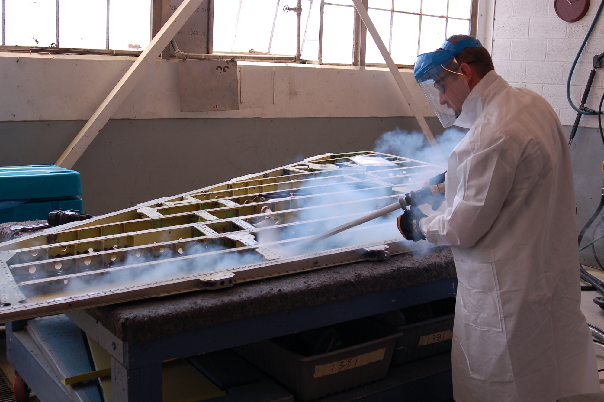 HILL AIR FORCE BASE, Utah — Mr. Dennis Hathaway, F-16 Wing Shop supervisor, blasts an F-16 left hand outer wing using a blast swath nozzle. (Air Force photo by Bill Orndorff)

