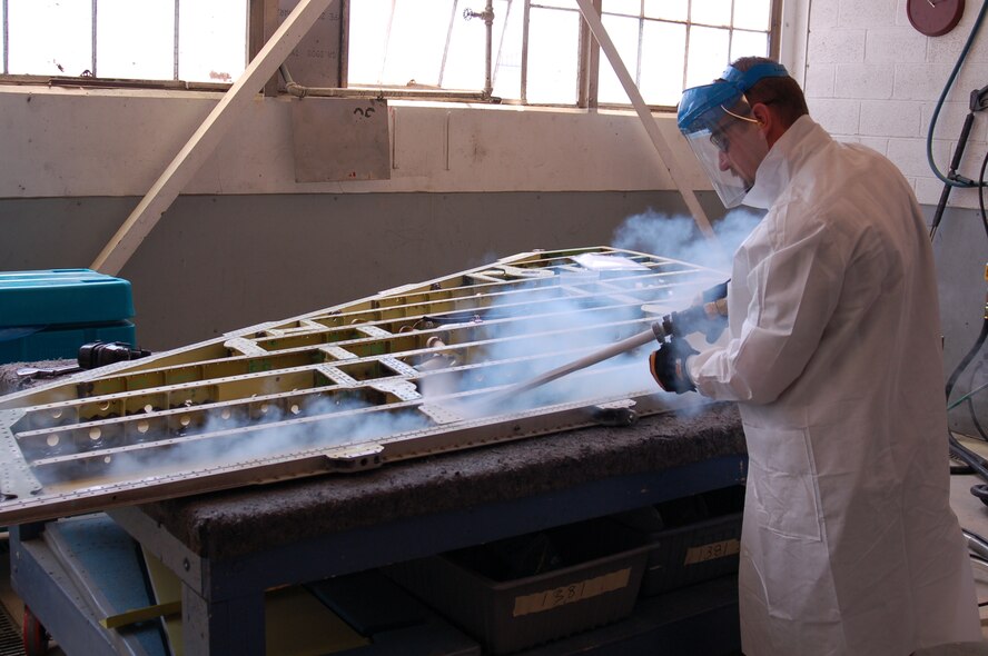 HILL AIR FORCE BASE, Utah — Mr. Dennis Hathaway, F-16 Wing Shop supervisor, blasts an F-16 left hand outer wing using a blast swath nozzle. (Air Force photo by Bill Orndorff)


