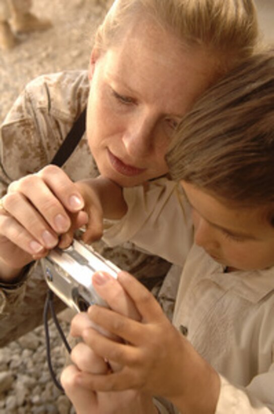 U.S. Marine Lt. Col. Deborah McCommell shows an Afghan child how to operate a digital camera at the Korean Hospital celebration on Bagram Airfield, Afghanistan, June 15, 2006. 