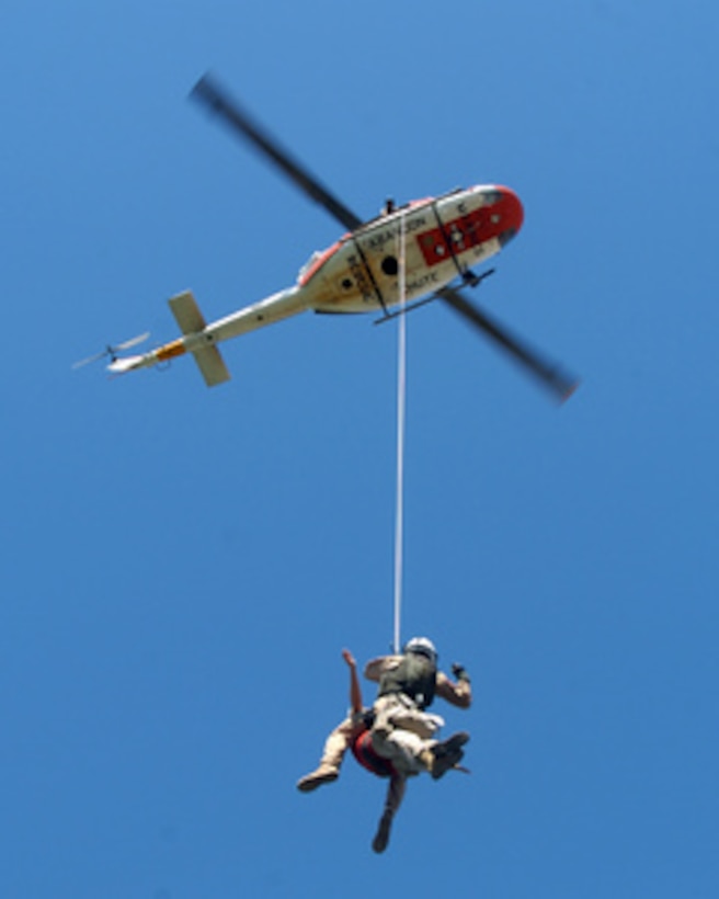 U.S. Navy Petty Officer 1st Class Jason Conley and U.S. Marine Capt. Dawn Steinberg hang from a UH-1N Huey search and rescue helicopter during a training exercise over Lake Martinez, Ariz., on June 16, 2006. Conley and Steinberg are with Headquarters and Headquarters Squadron, Marine Corps Air Station Yuma, Ariz. 